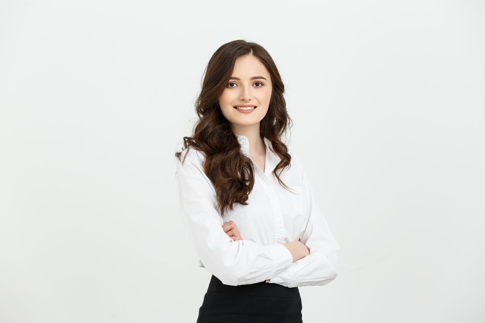 Smiling woman in a white blouse with arms crossed against a light background